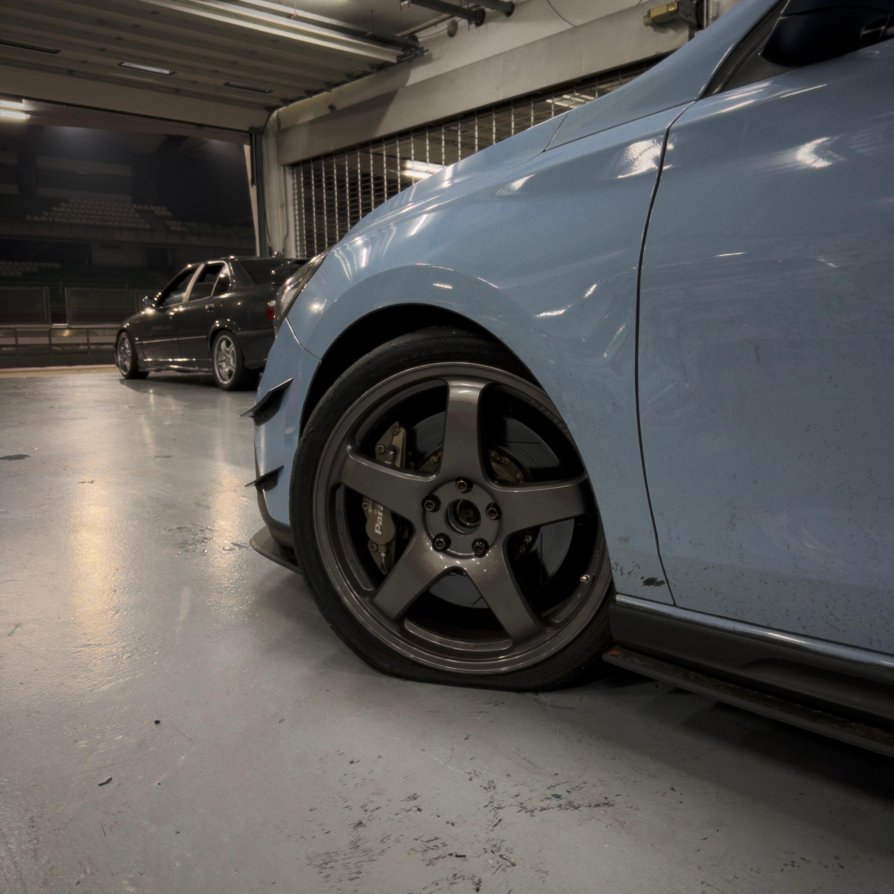 Pit garage detail — Enkei PF05 gunmetal 5-spoke with Paragon big brake, flat tyre