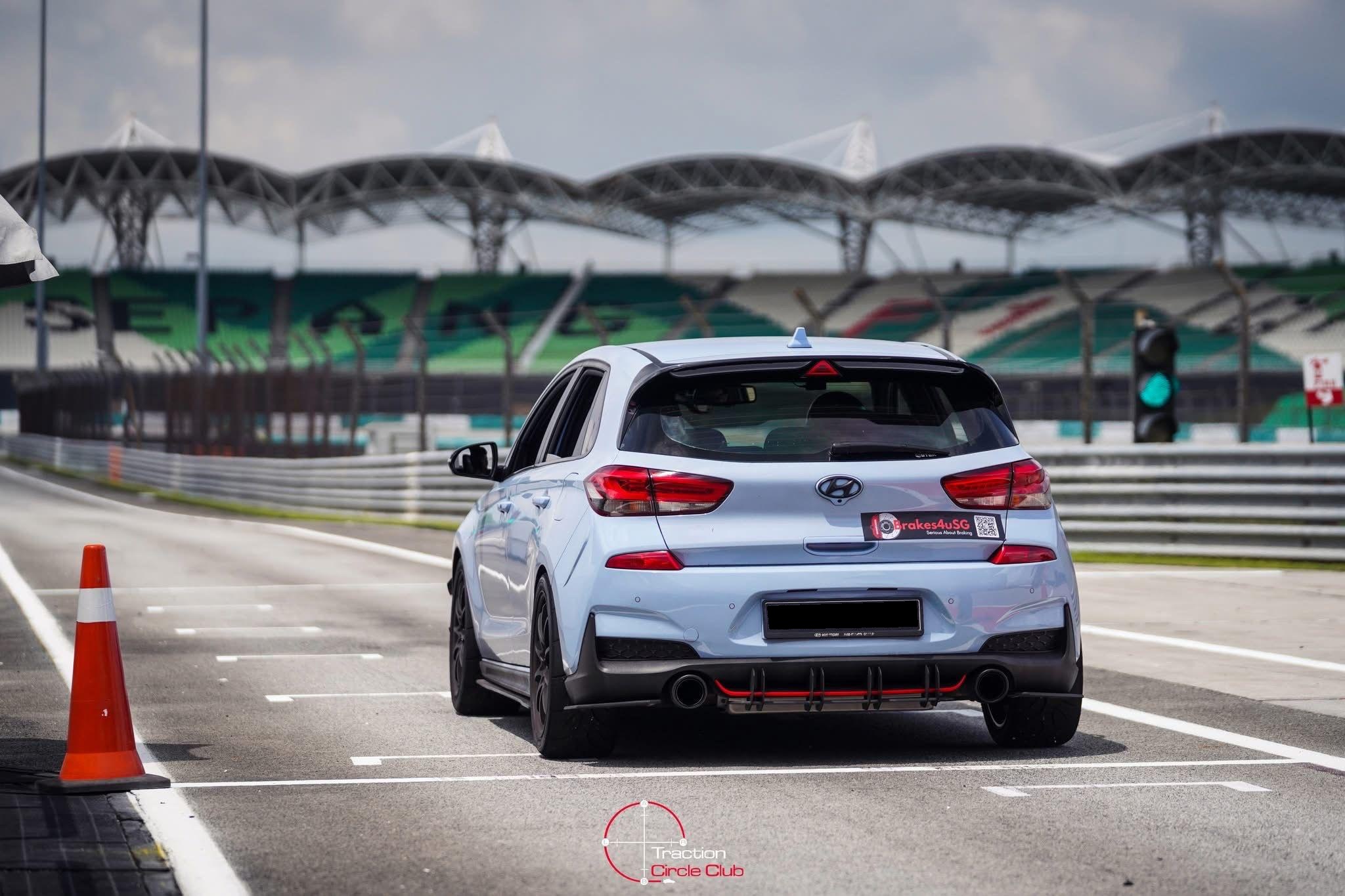 Rear three-quarter at the pit exit, SEPANG signage and grandstand canopy in the background, green light