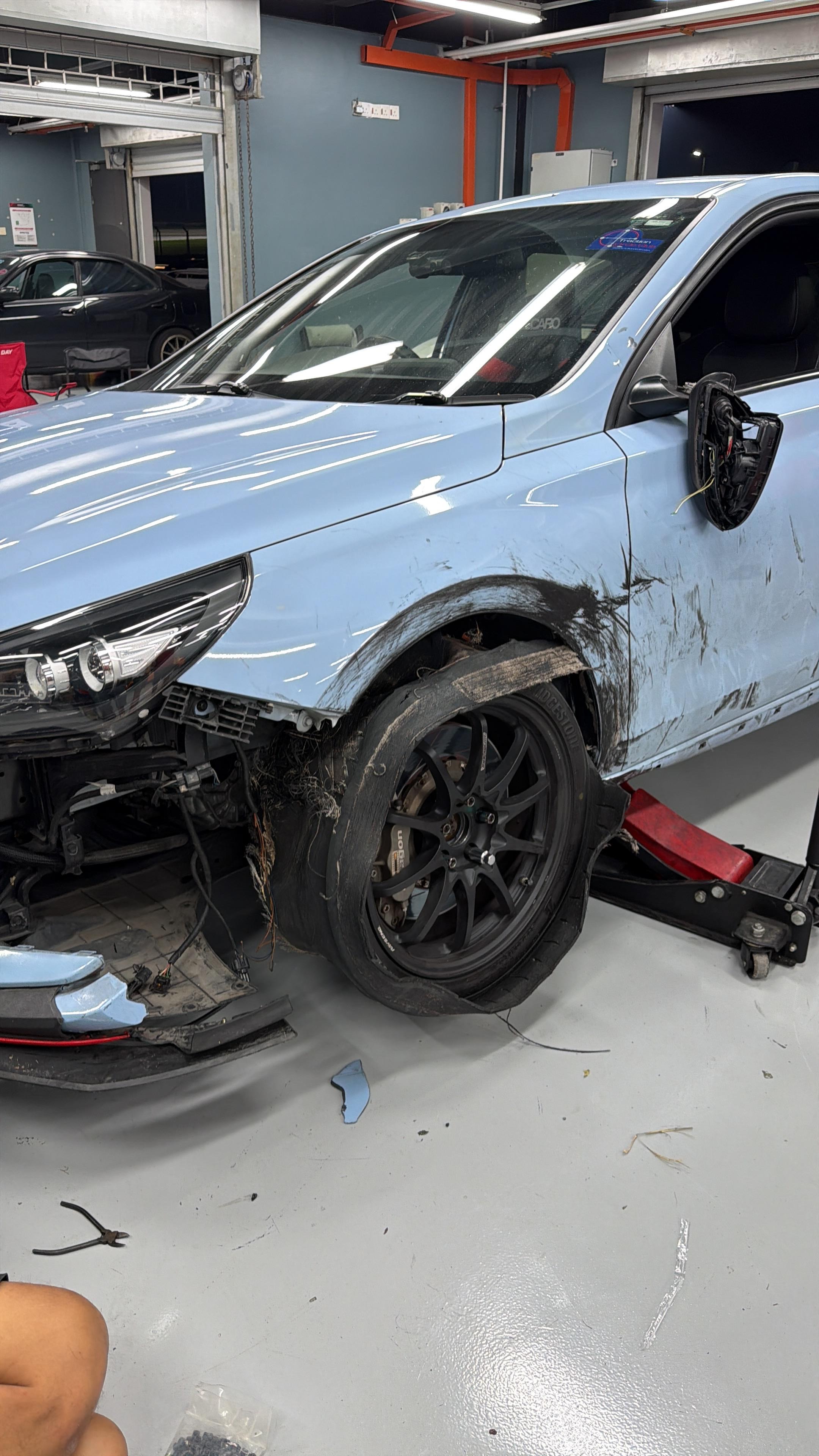 South pits, Sepang, front tyre shredded to the cords still fitted, car on a jack right after the blowout to assess the damage