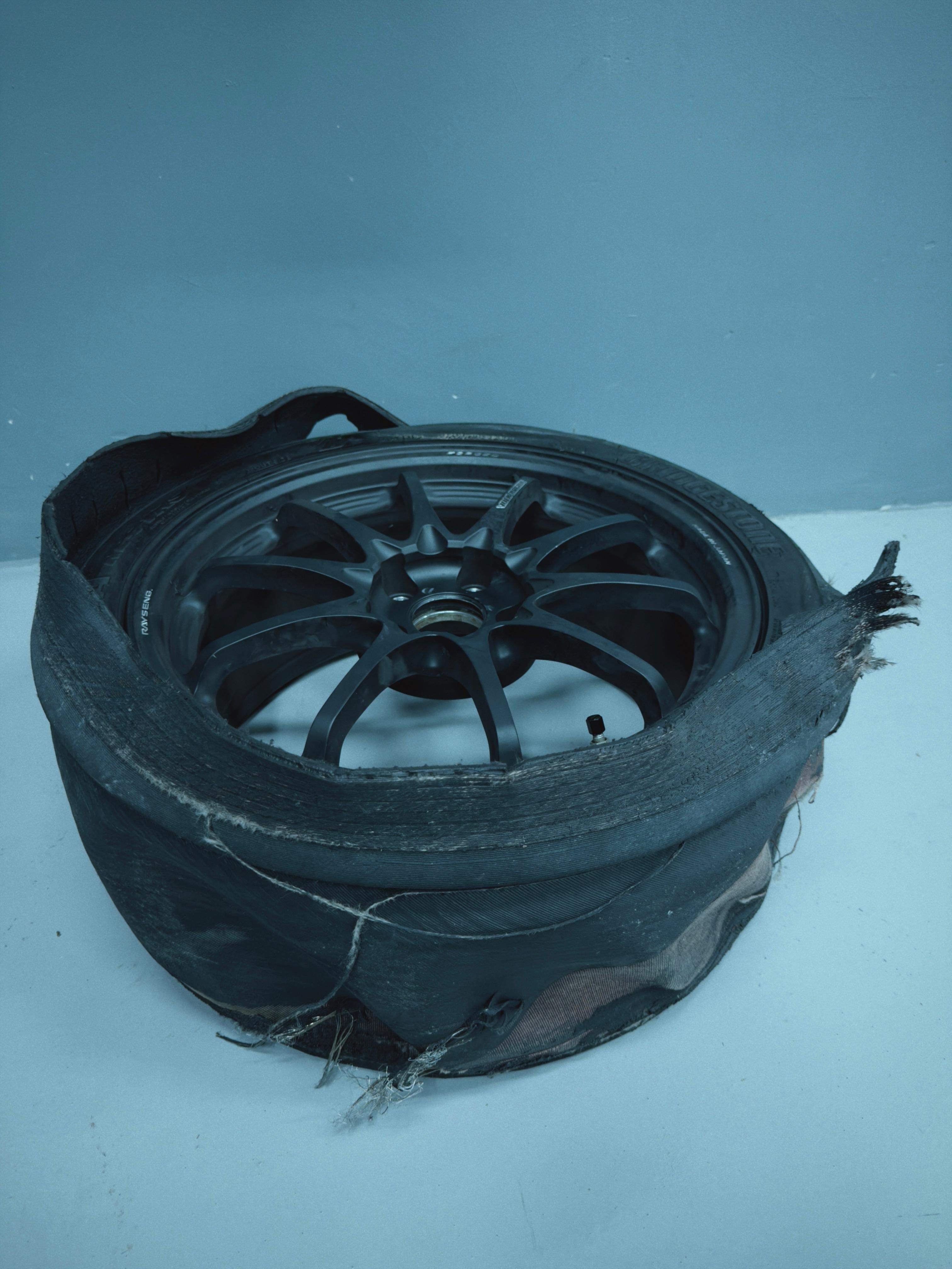 Destroyed Bridgestone tyre collapsed around a forged ten-spoke wheel, south pits