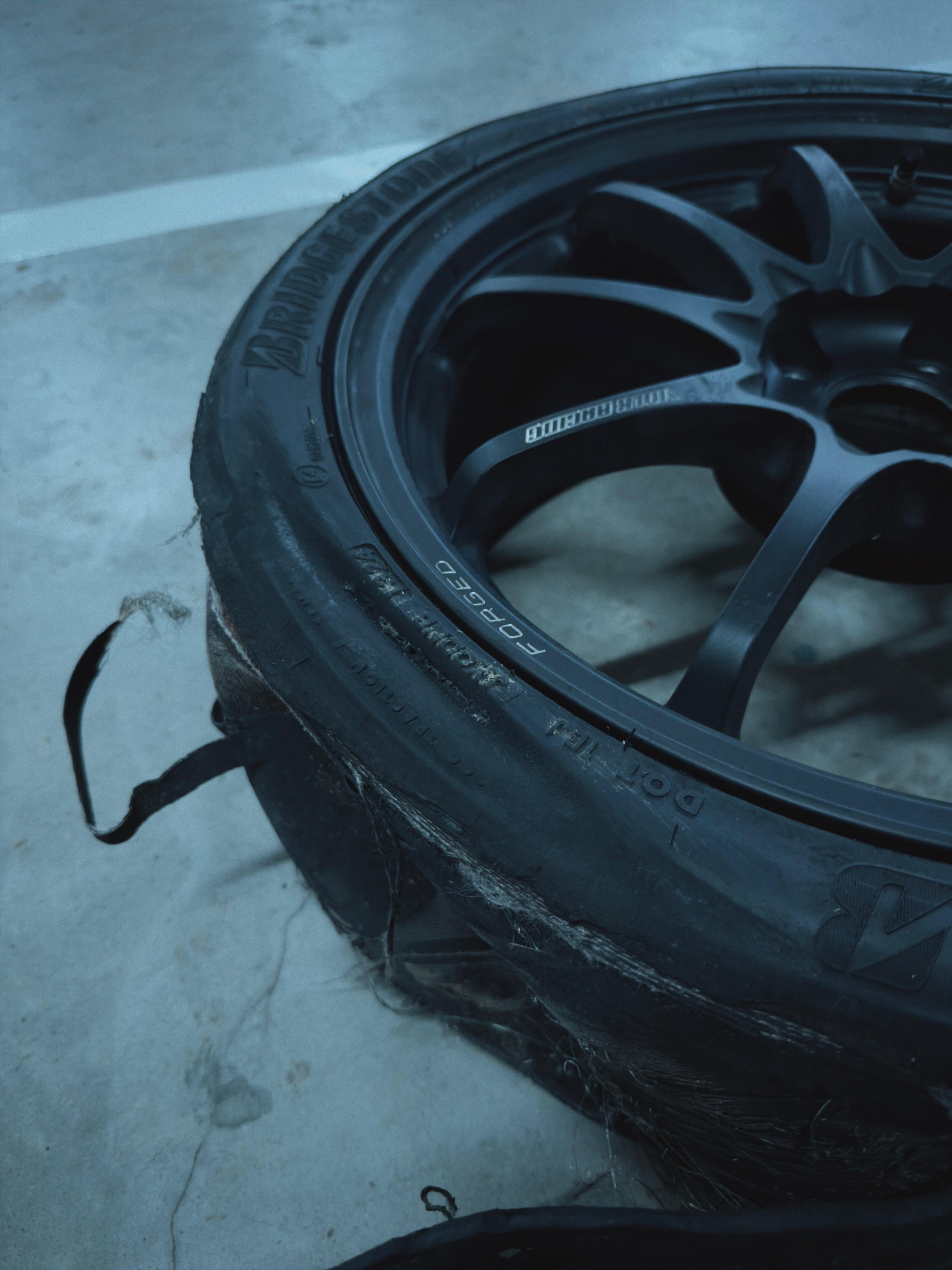 Debeaded tyre hanging off the forged wheel, cords and carcass exposed, south pits