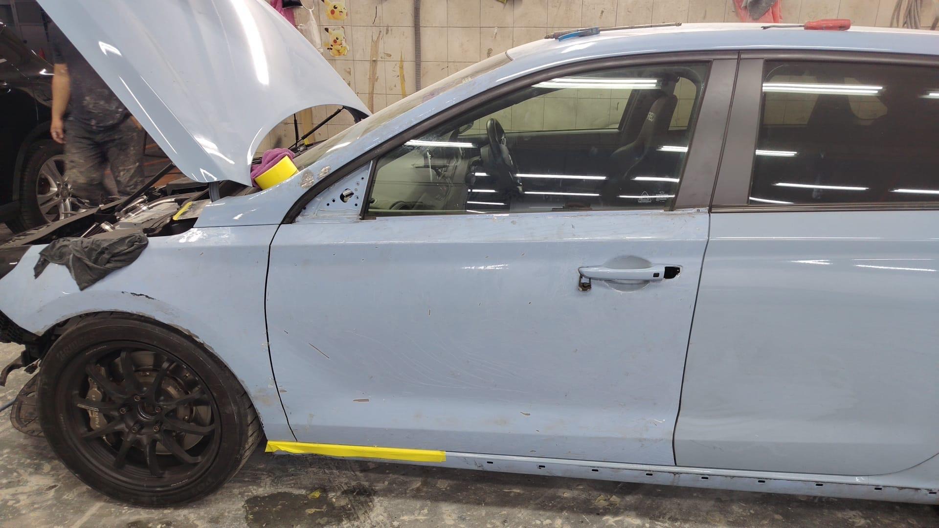Left side masked with tape for paint, hood up in the booth