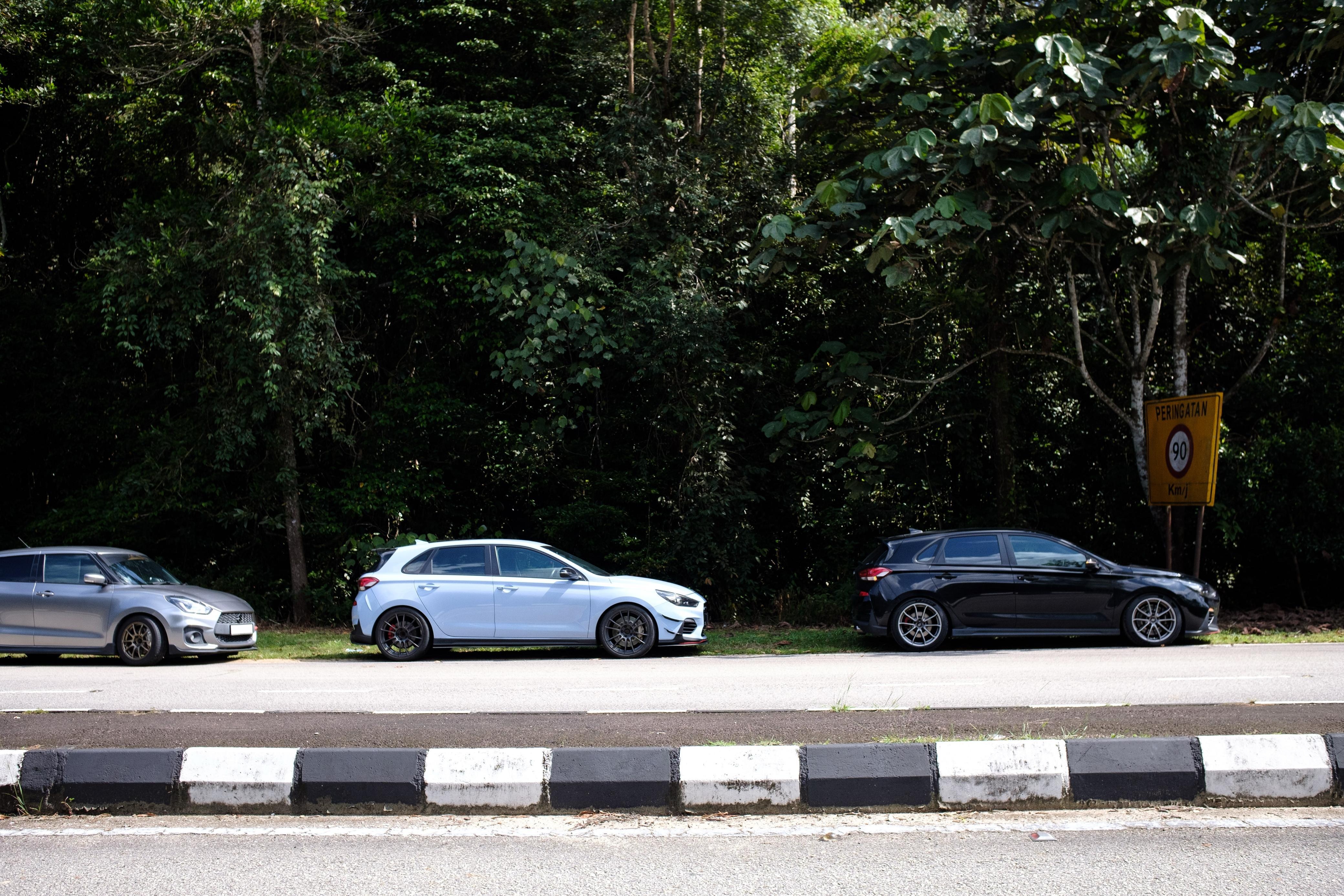 Roadside lineup with a Swift and a black i30 N, Johor jungle backdrop